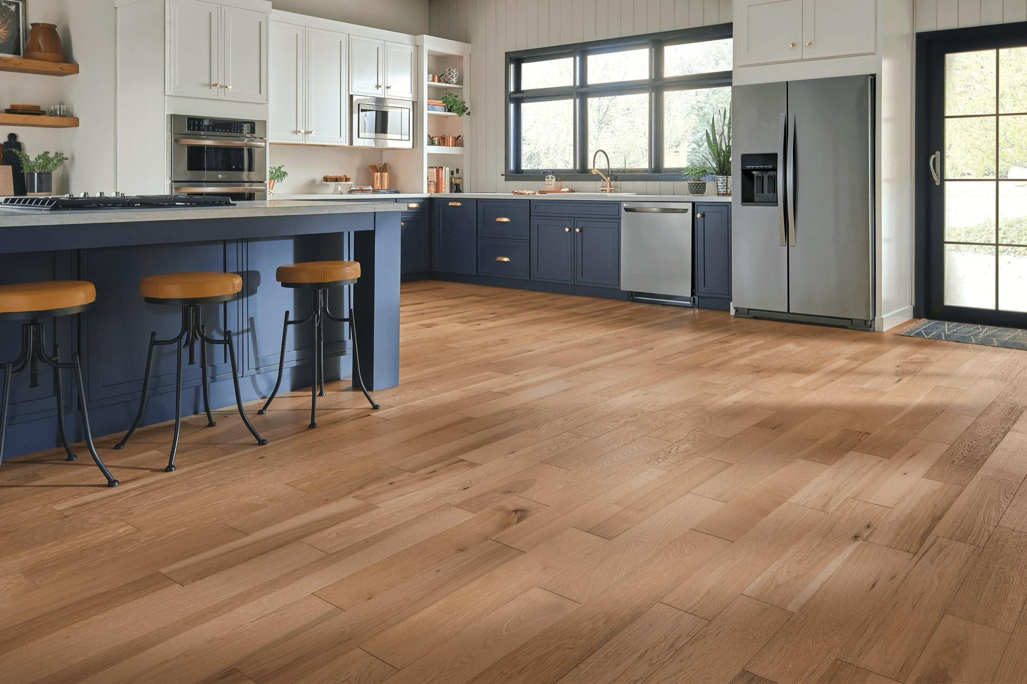Wide-plank Bruce solid oak hardwood in an open kitchen with a navy island