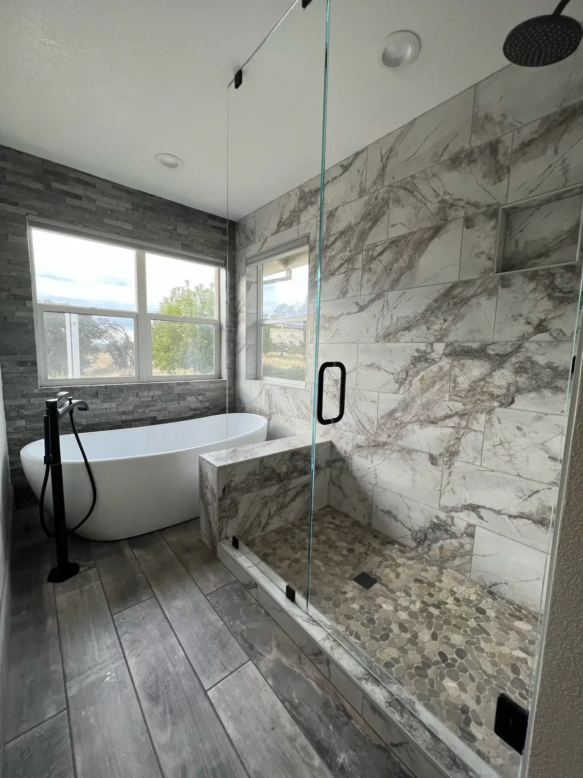 Carrara marble bathroom with a soaking tub set beneath a window
