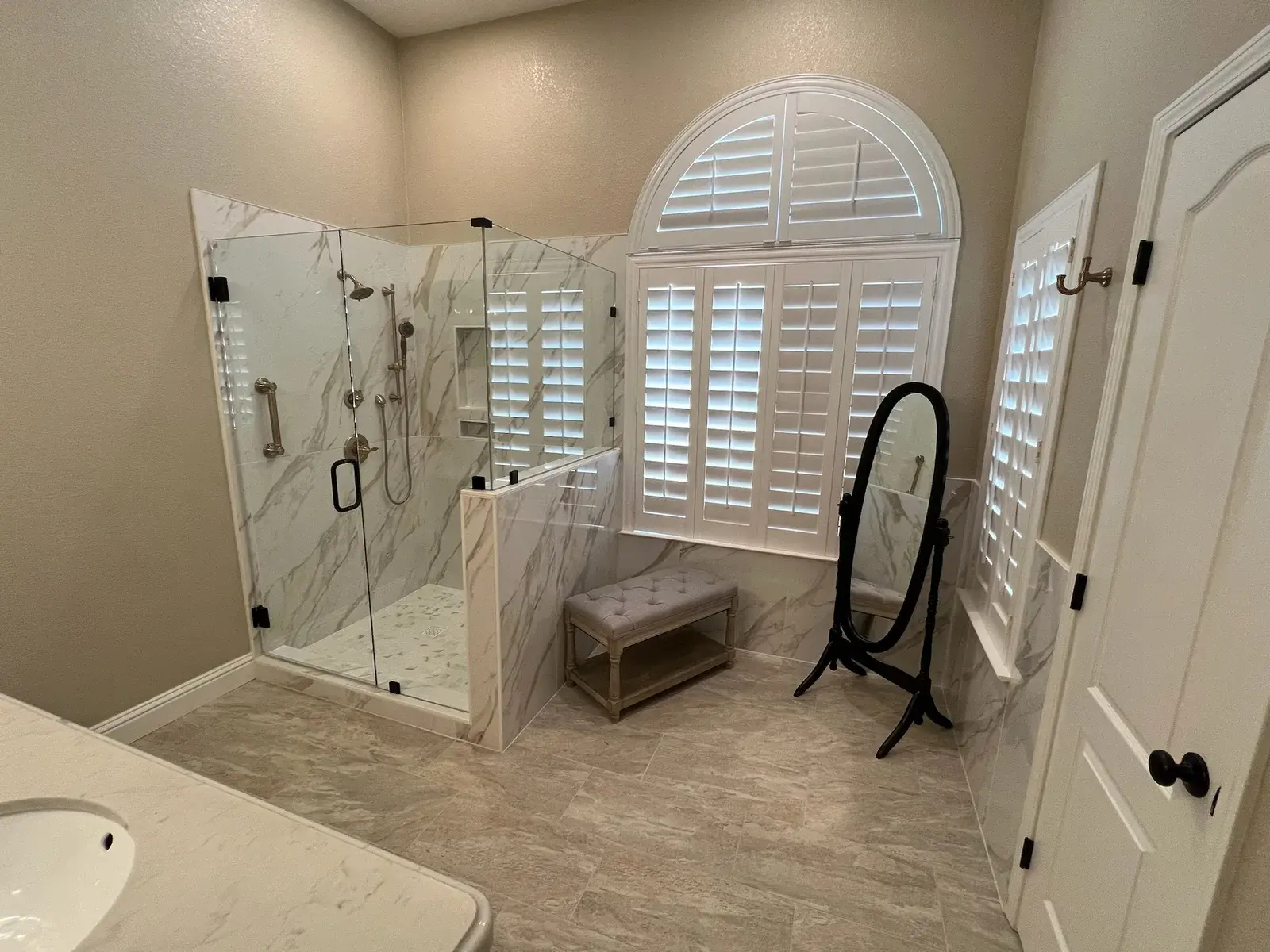 Master bathroom with a marble glass shower, plantation shutters, and a bench