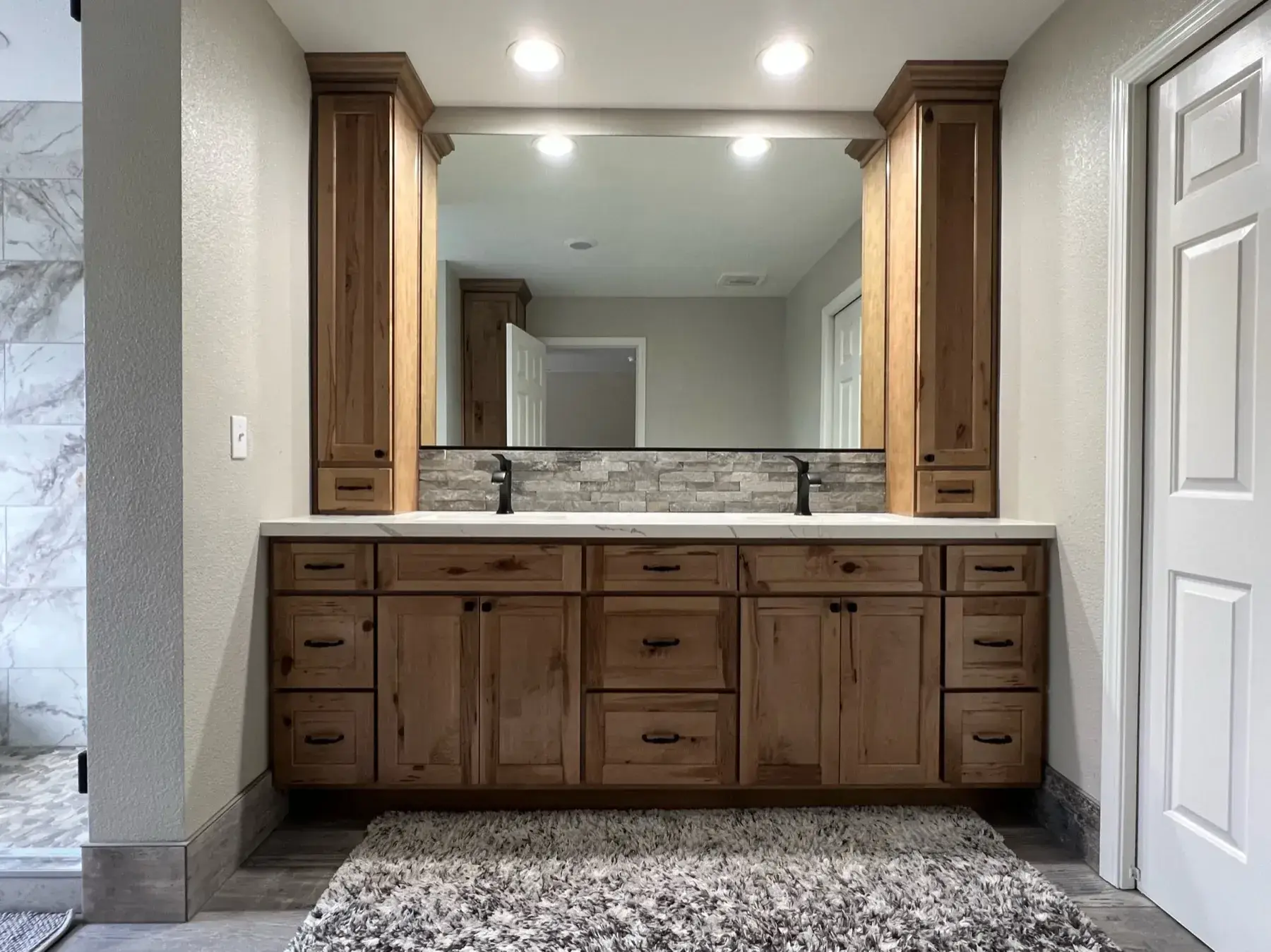 Spa-like bathroom with a knotty alder double vanity, stone backsplash, and large mirror