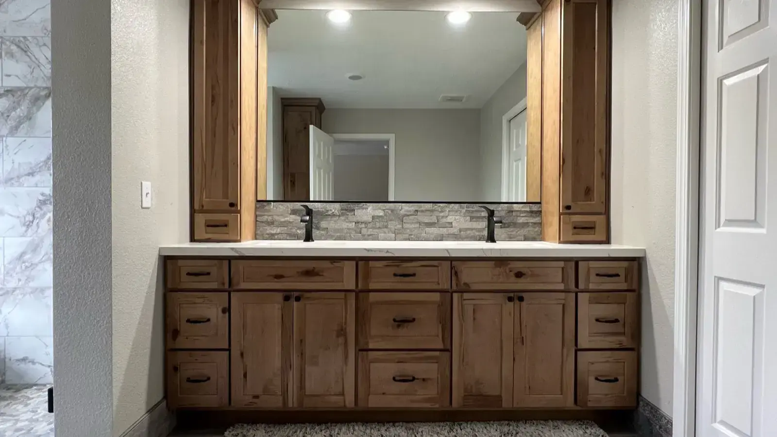 After: Rustic wood double vanity with a framed mirror and stone backsplash after remodel