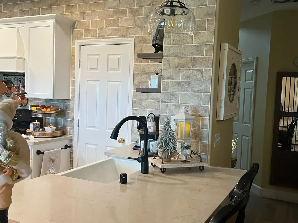 Quartz peninsula with a black faucet and a brick-look tile backsplash