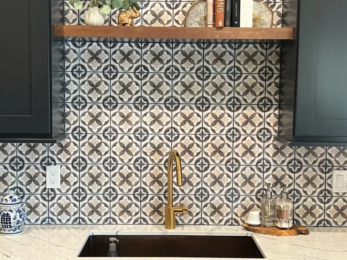 Quartz countertop with a gold faucet and a hand-painted marble tile backsplash