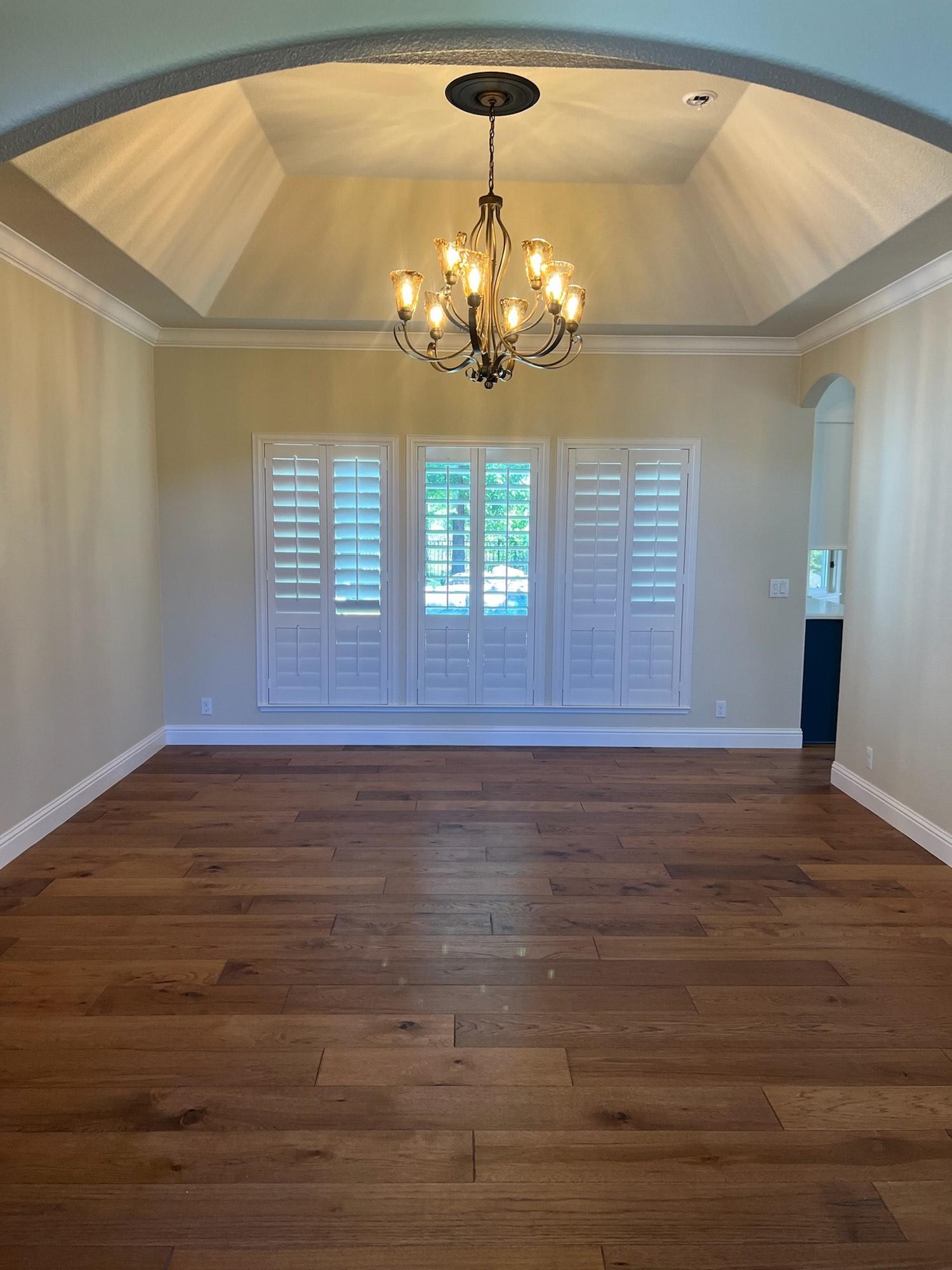 Elegant dining room with dark hardwood floors, a tray ceiling, and a crystal chandelier.
