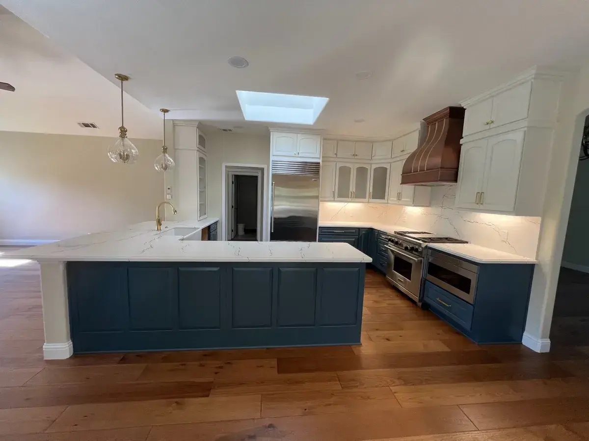 Finished kitchen remodel with a navy island, quartz counters, and a custom wood range hood