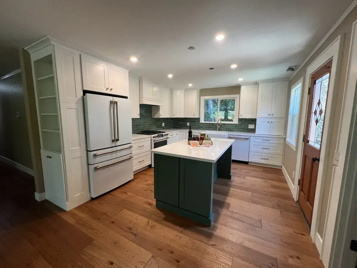 Finished kitchen remodel with white cabinets, a green island, and hardwood floors