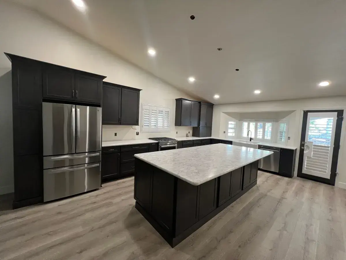Finished open kitchen with dark cabinets and a white quartz waterfall island