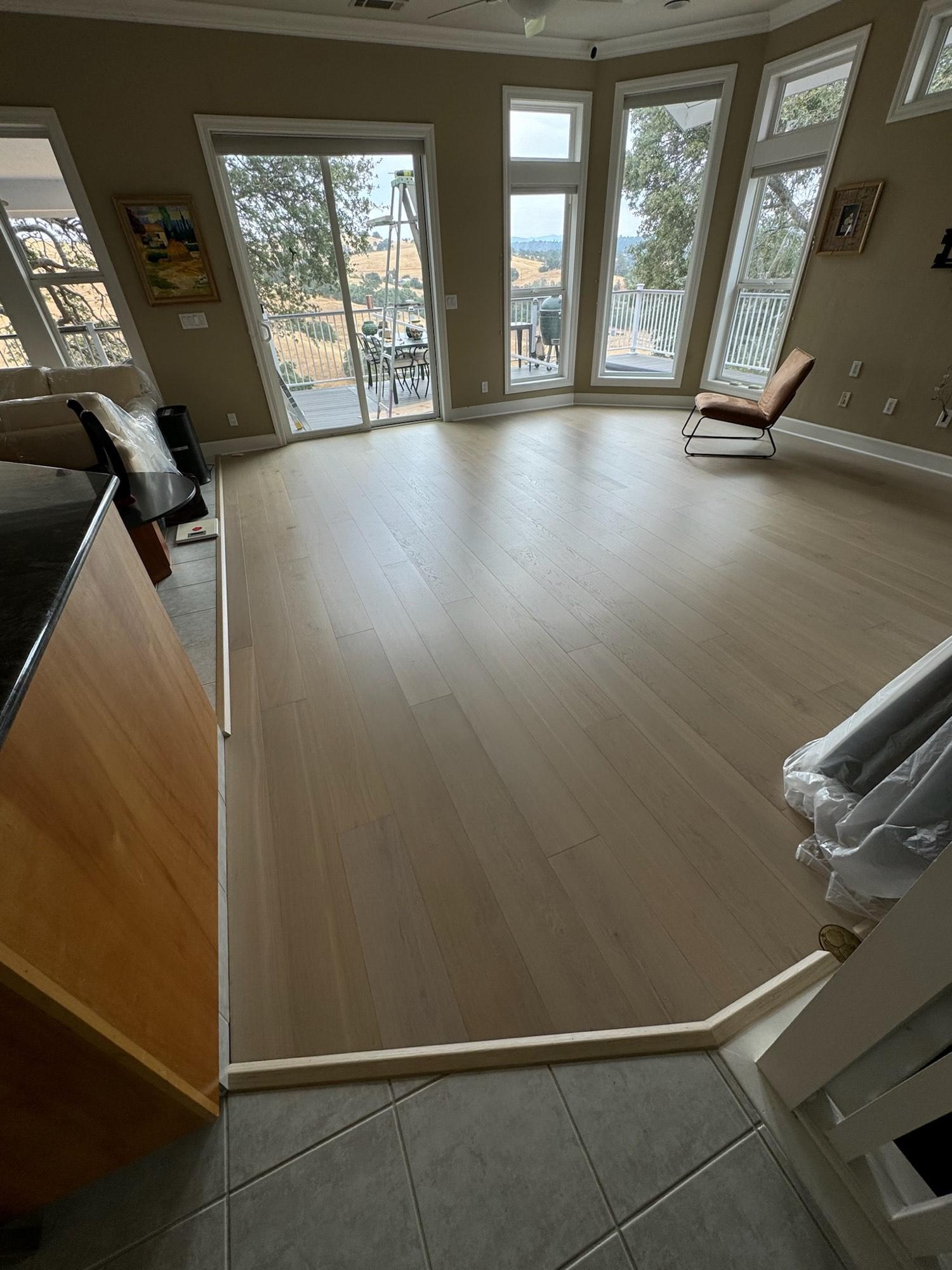 A sunlit living room with newly installed hardwood floors